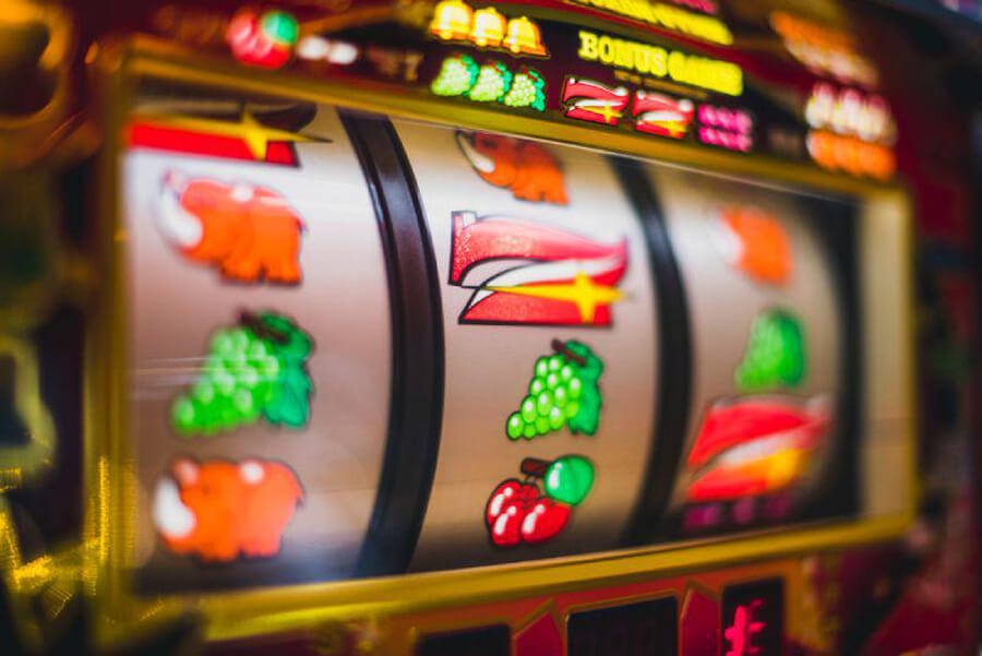 Close-up of spinning reels of a slot machine with fruit symbols such as grapes, cherries, and oranges.